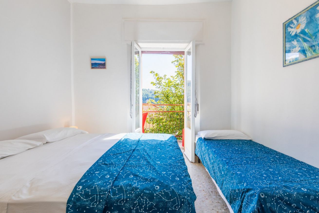 Ein Zimmer mit zwei Betten, einem Balkon und einem Bild an der Wand.