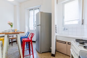 Eine kleine Küche mit Kühlschrank, Herd und Fenster.