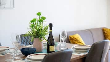 Une table à manger dressée avec des assiettes, des verres, une bouteille de vin et une plante en pot.