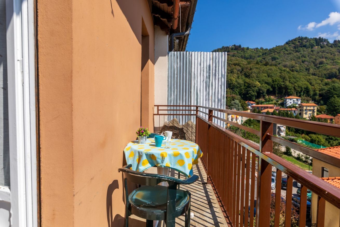 Ein Balkon mit Tisch und Stühlen mit Blick auf eine Hügellandschaft mit Gebäuden.