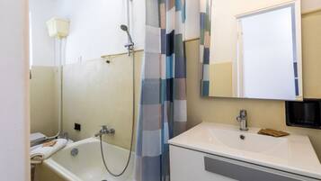 Ein Badezimmer mit Badewanne, Waschbecken, Spiegel und Duschvorhang.