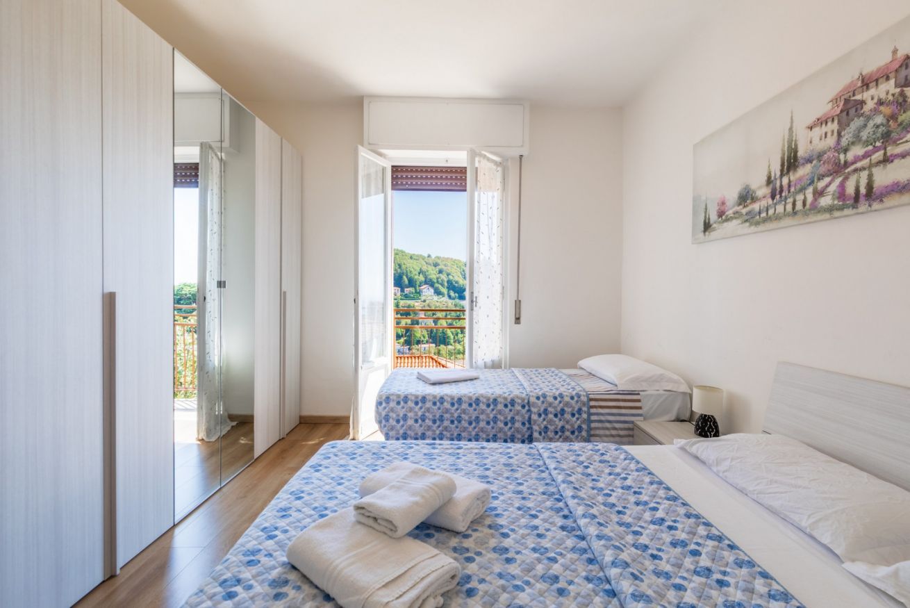 Ein Schlafzimmer mit zwei Betten, einem großen Fenster und einem Gemälde an der Wand.