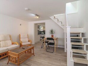 Ein modernes Wohnzimmer mit einer Couch, Sesseln, einem Couchtisch und einer Treppe.