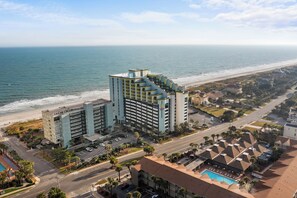 A coastal hotel with multiple floors, a parking garage, and a swimming pool. - The Sea Suite  10th-Floor Corner Unit with Panoramic Ocean Views & Rooftop Pool (Myrtle Beach)