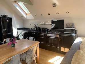 A compact kitchen with a dining area, a built-in oven, a microwave, and a stove. - Upside Down House 4 Double bedrooms 4 en suite Bathrooms  Dog friendly (Dell Quay)