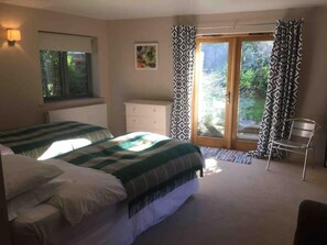 Ein Schlafzimmer mit einem Bett, einem Schminktisch, einem Sessel und einem Fenster mit Vorhängen.