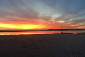 A beach with a calm sea and a sunset. - Upside Down House 4 Double bedrooms 4 en suite Bathrooms  Dog friendly (Dell Quay)