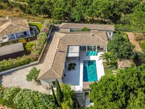 Ein großes Haus mit Swimmingpool, mehreren Terrassen und üppigem Grün.