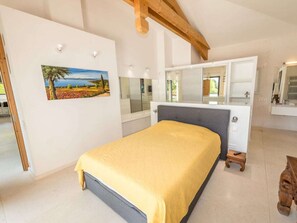 Ein Schlafzimmer mit einem Bett, einem Schminktisch, einem Spiegel und einem Bild an der Wand.