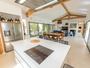 Eine moderne Küche mit einer zentralen Kochinsel, eingebauten Geräten und einem Essbereich mit großem Tisch und Stühlen.