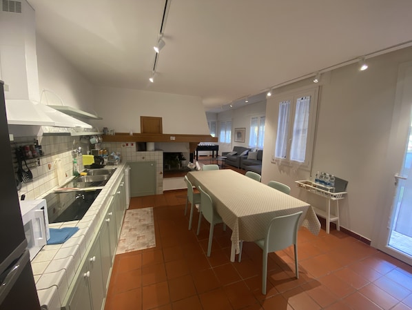 Una cocina moderna con comedor, un piano y un sofá en la sala de estar.