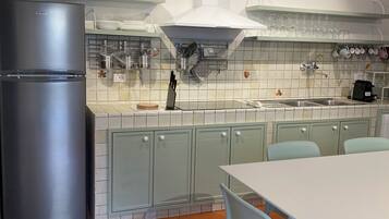 Una cocina moderna con un refrigerador de acero inoxidable, una mesa de comedor blanca con sillas y un salpicadero de azulejos.