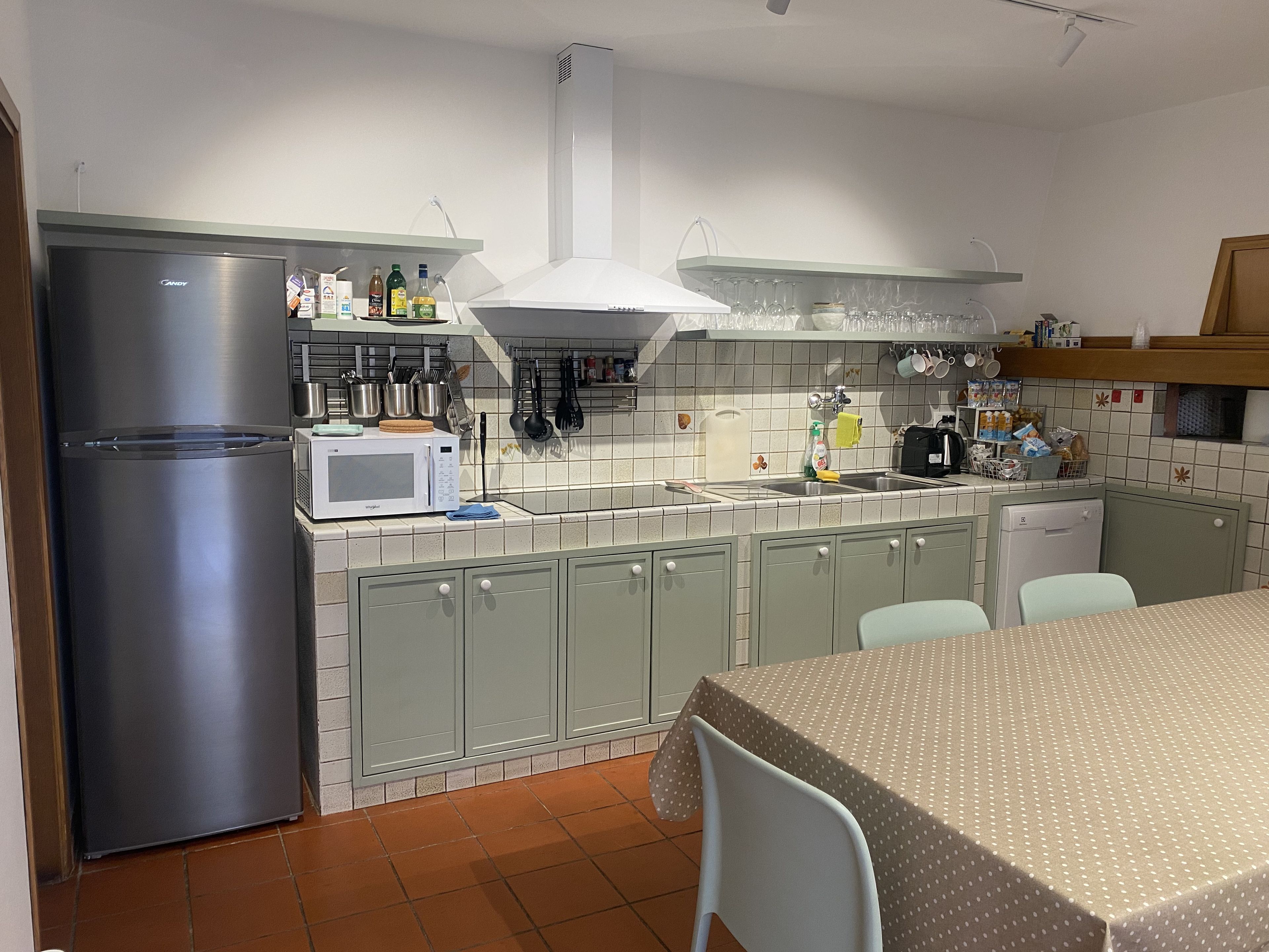 A kitchen with a stainless steel refrigerator, a microwave, a sink, and a dining table with chairs.