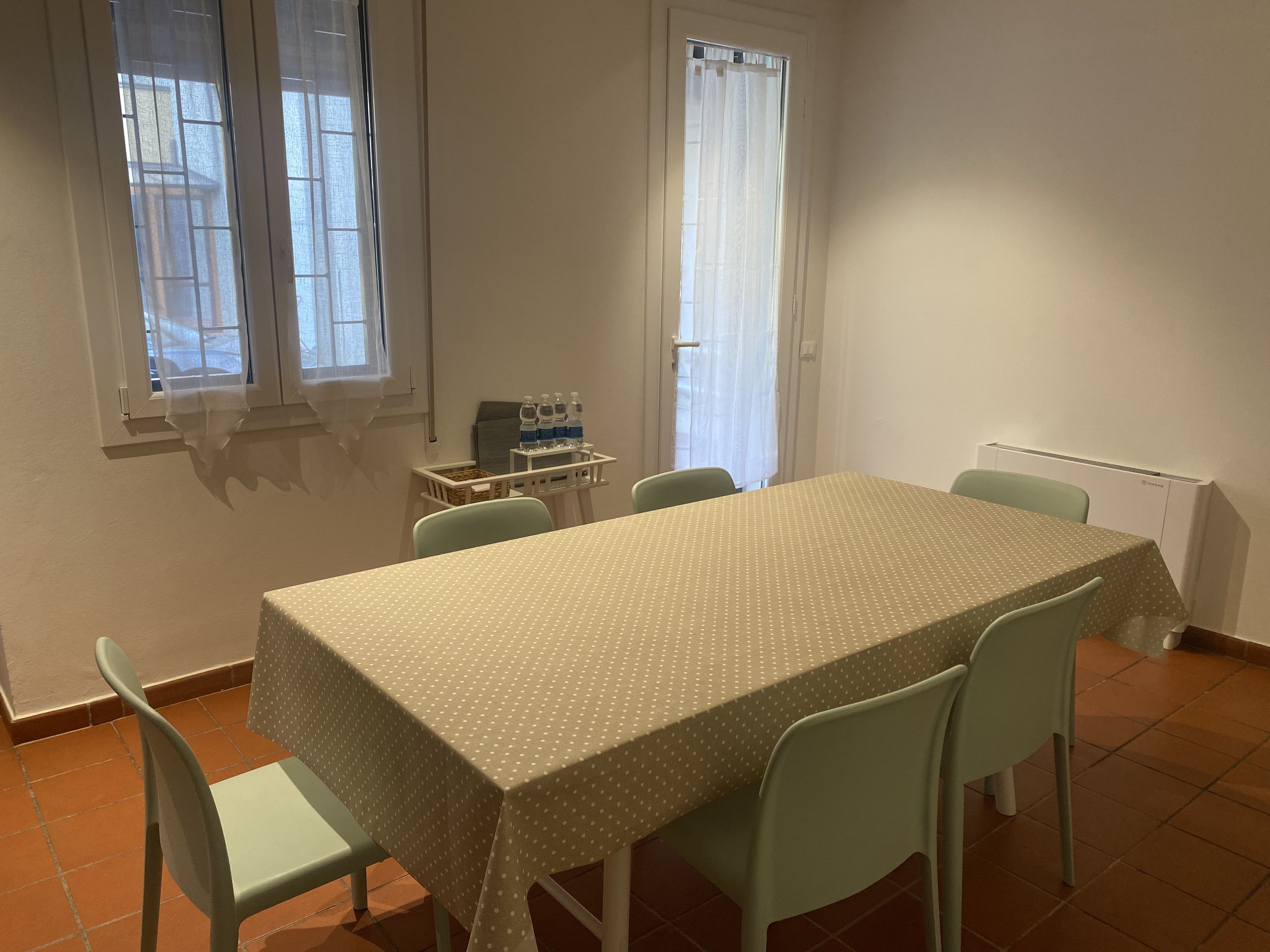Un coin repas avec une table et des chaises, un radiateur et une fenêtre avec des rideaux.