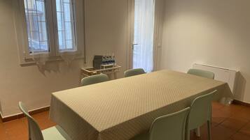 Un coin repas avec une table et des chaises, un radiateur et une fenêtre avec des rideaux.