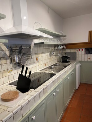 A kitchen with a stove, sink, and cabinets.