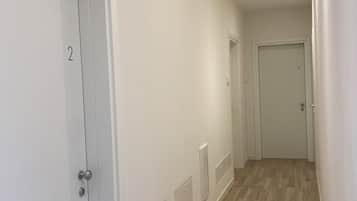 En gang med hvide døre nummereret 2 og 4, trægulv og indbyggede loftslamper.
