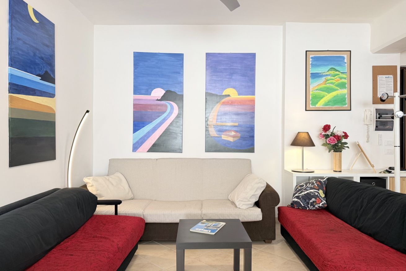 A room with a sofa set, a coffee table, and two paintings on the wall.