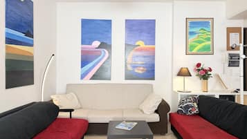 A room with a sofa set, a coffee table, and two paintings on the wall.