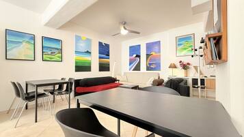 Un espacio habitable moderno con comedor, sofá y obras de arte en las paredes.