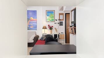 A compact room with a bed, a desk, a chair, a bookshelf, and a door.