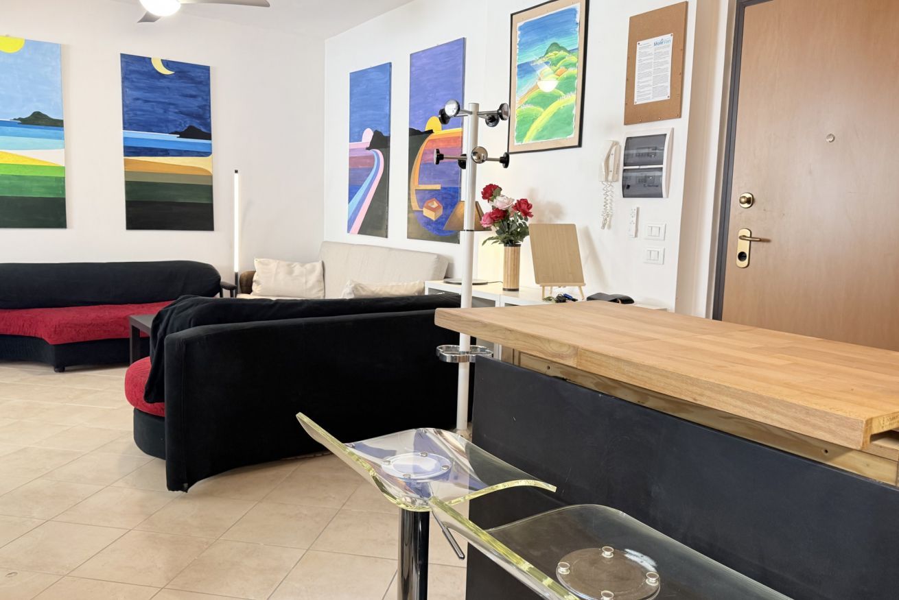 A room with a reception desk, a black couch, a red couch, and artwork on the walls.