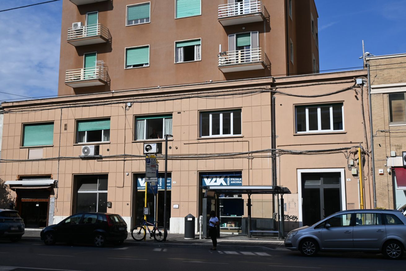 Un edificio de varios pisos con una tienda en la planta baja, una entrada visible y una bicicleta estacionada afuera.