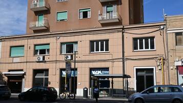 Un edificio de varios pisos con una tienda en la planta baja, una entrada visible y una bicicleta estacionada afuera.