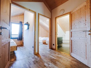 A wooden interior with a loft bedroom, a bathroom, and a kitchen area. - One-bedroom Cabin (Sankt Georgen am Kreischberg)