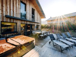 A wooden building with a deck, outdoor seating, and a hot tub. - One-bedroom Cabin (Sankt Georgen am Kreischberg)
