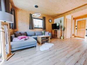 A cozy living room with a sofa, coffee table, and a television. - One-bedroom Cabin (Sankt Georgen am Kreischberg)