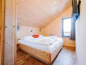 A wooden room with a bed, a window, and a wall-mounted light fixture. - One-bedroom Cabin (Sankt Georgen am Kreischberg)