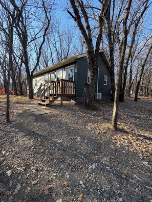 A house with a porch, surrounded by trees and a gravel driveway.