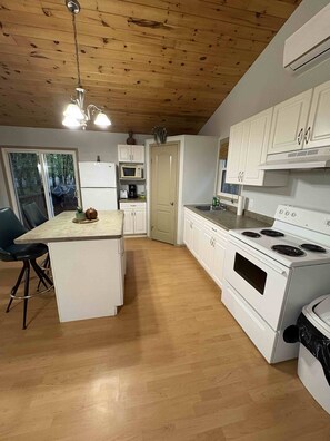 A kitchen with wooden flooring, white cabinets, a built-in oven, and a dining area with a table and chairs.