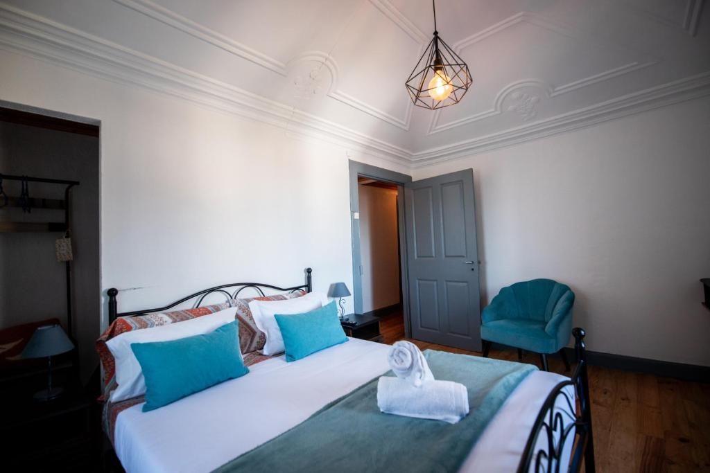 A hotel room with a bed, a chair, a door, and a hanging light fixture.