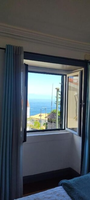 Una habitación con un ventanal grande, una cama y vista al mar.