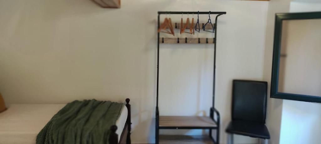 Una habitación con una cama, una silla y un perchero.