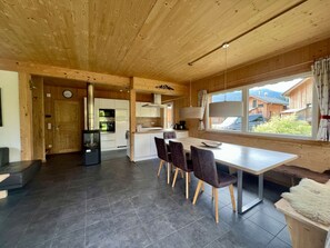 A modern kitchen with a dining area, wooden ceiling, and a view of the outside. - One-bedroom Cabin (Sankt Georgen am Kreischberg)