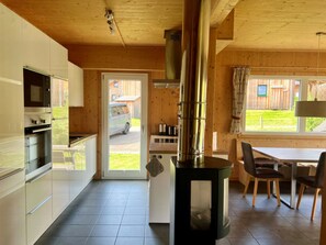 Eine moderne Küche mit Einbauherd, ein Essbereich mit Tisch und Stühlen sowie ein Blick ins Freie.