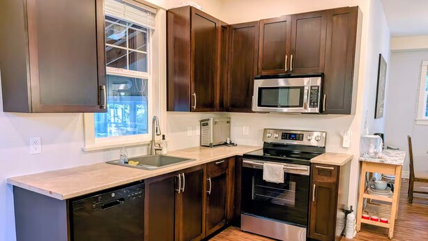A modern kitchen with dark wood cabinets, stainless steel appliances, and a wooden floor. - Comfortable private room near downtown Victoria (Victoria)