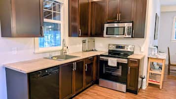 A modern kitchen with dark wood cabinets, stainless steel appliances, and a wooden floor.