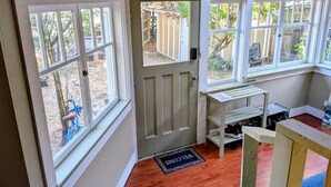 A room with a door, windows, a welcome mat, and a small table with shelves. - Comfortable private room near downtown Victoria (Victoria)
