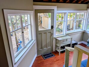 A room with a door, windows, a welcome mat, and a small table with shelves. - Comfortable private room near downtown Victoria (Victoria)
