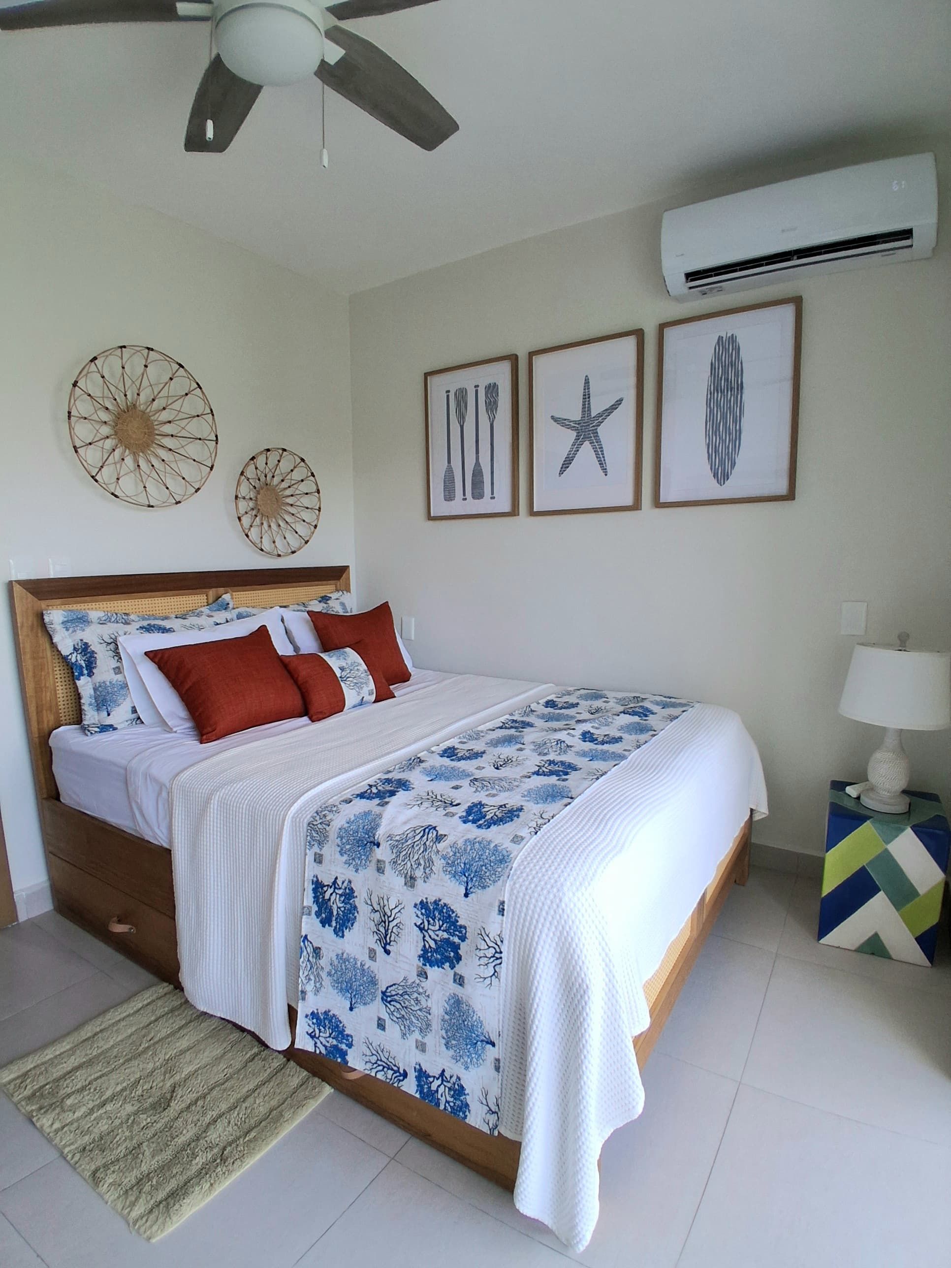 Un dormitorio con cama, ventilador de techo, aire acondicionado y decoración en la pared.