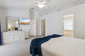Ein Schlafzimmer mit Bett, Schminktisch, Spiegel und Deckenventilator.