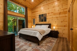 Un dormitorio con paneles de madera, una cama, lámparas de noche y vistas al exterior.