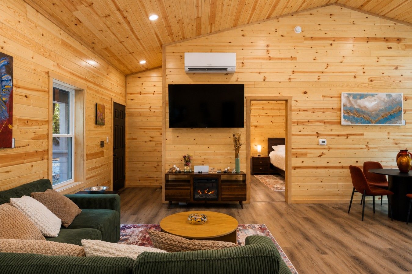 Un intérieur de chalet chaleureux, avec un revêtement en bois, un téléviseur à écran plat, une cheminée et un coin repas.
