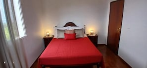 Een slaapkamer met een bed, twee nachtkastjes en een deur.
