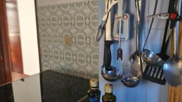 A kitchen with a stove, two bottles of olive oil, and a clock on the wall.