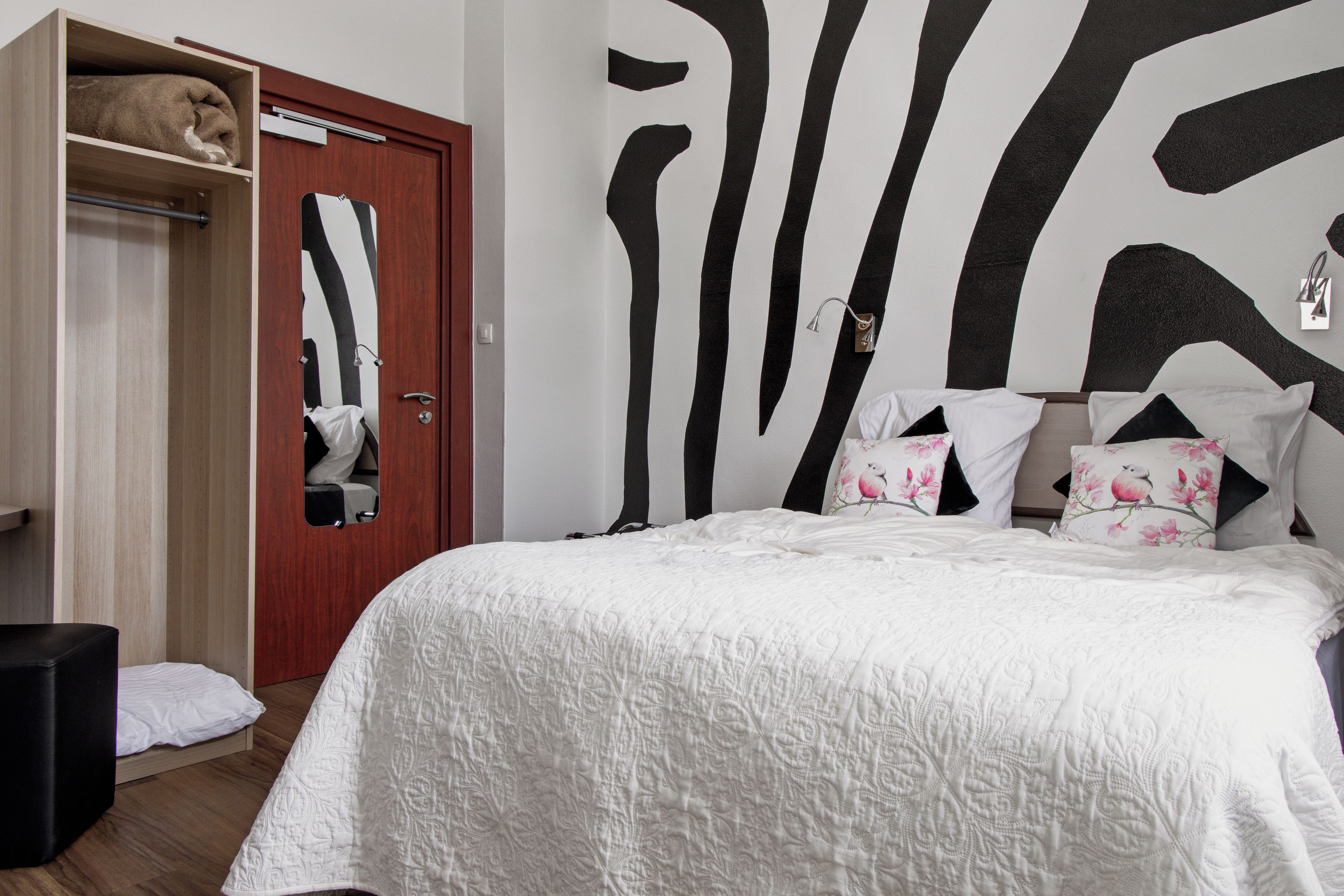 A bedroom with a bed, a wardrobe, and a mirror.